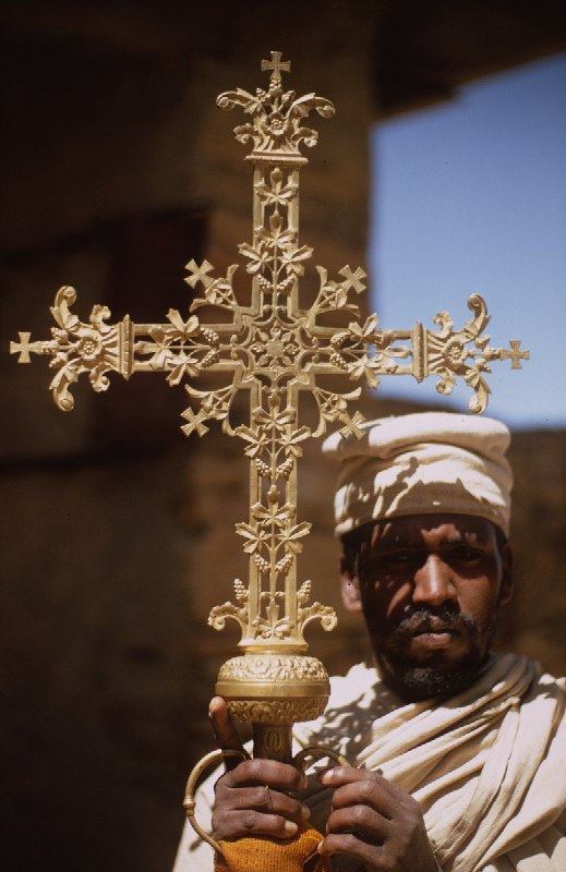 一位僧人在德布雷达摩山修道院展示一枚精美细致的金质讲道十字架，1960年代