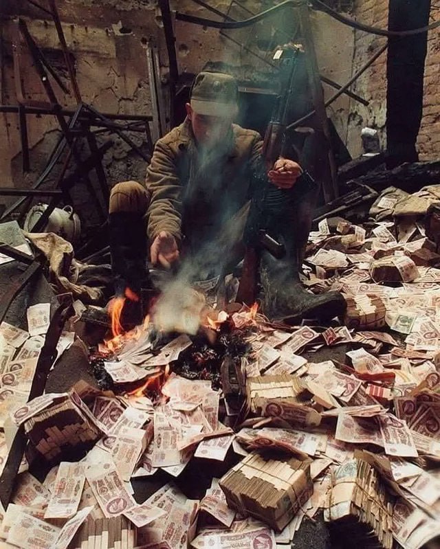1995 年在车臣战争期间，一名俄罗斯士兵为了取暖，将废弃或贬值的苏联纸币点燃燃烧