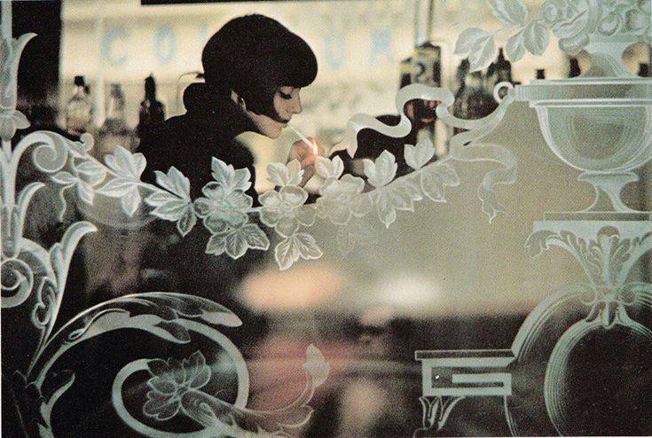 一位女士在咖啡館窗邊點燃香煙，巴黎，戈登·帕克斯 (Gordon Parks) 攝 (1964)