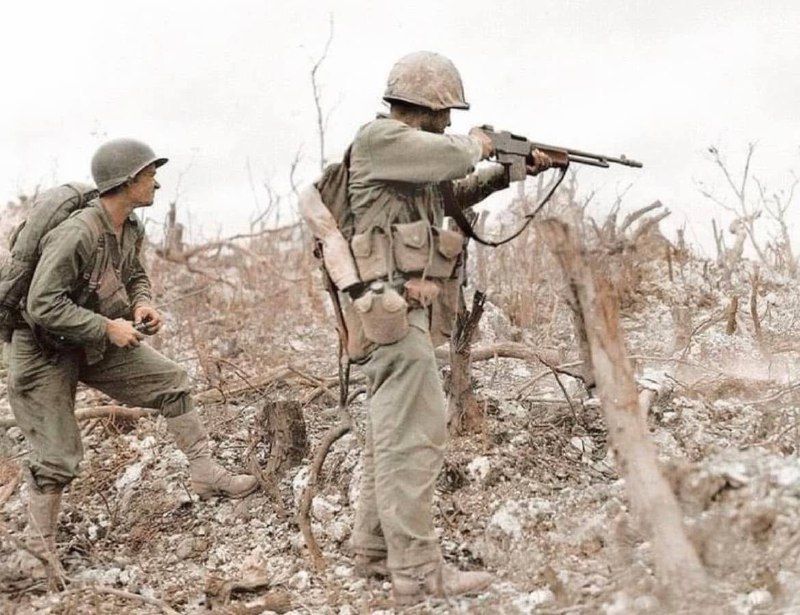 1945 年，沖繩戰役期間，一名 BAR 士兵瞄準，而另一名士兵正準備拉開手榴彈的引信