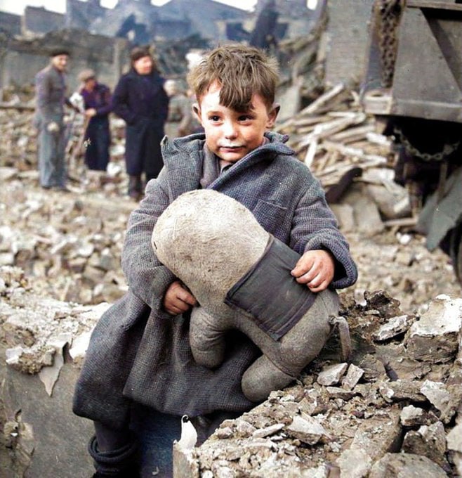 1940年，德国空袭伦敦后，一个被遗弃的男孩在废墟中抱着毛绒玩具动物