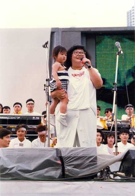 1989年5月27日，民主歌声献中华 (英语：Concert For Democracy In China）是香港市民为支持北京八九民运而举办的筹款活动，在跑马地马场举行，无线电视翡翠台、亚洲电视本港台、香港电台第一台、香港商业电台商业一台联合现场直播