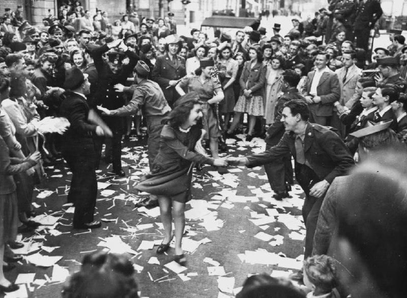 1945 年 5 月 8 日，即纳粹德国向盟军投降后的第二天，英国妇女在伦敦与美国士兵共舞