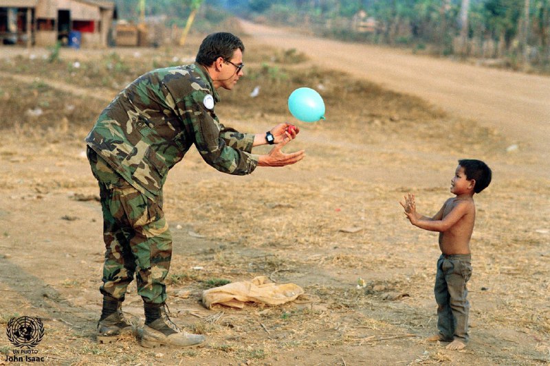 1993年3月1日，柬埔寨，一位联合国军事观察员与孩子玩接球游戏