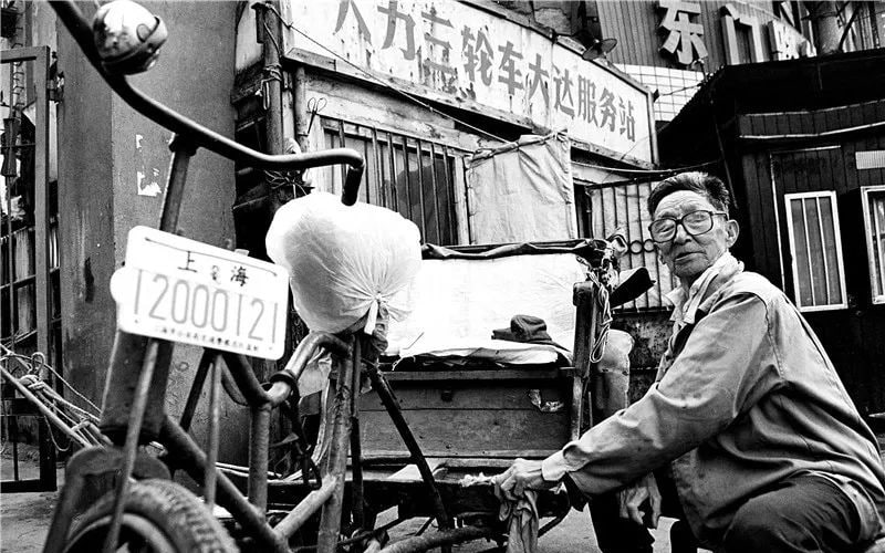 1986 年 5 月，上海最后一辆有牌照的人力脚踏三轮车，工人正在十六铺人力三轮车大达服务站门前擦车准备接客