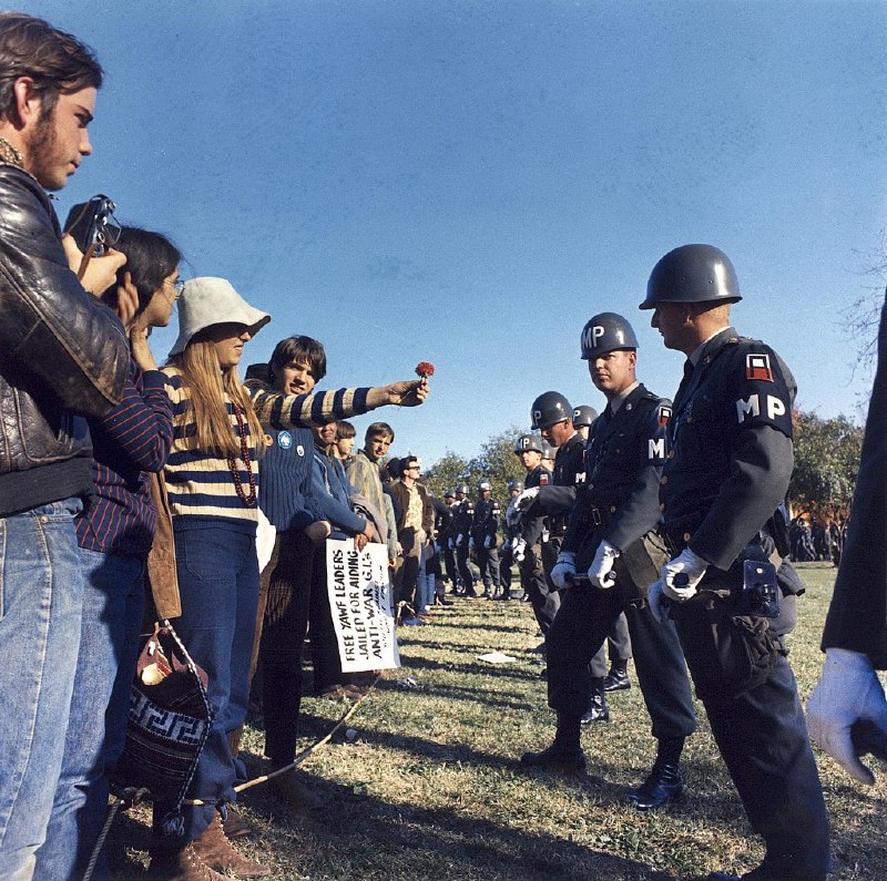 1967 年五角大楼举行的结束越南战争全国动员委员会会议期间，一名反战示威者向一名宪兵献花