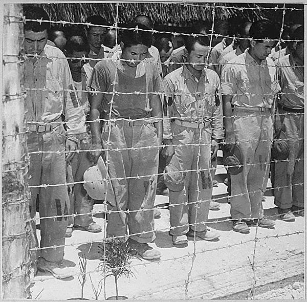 1945 年 8 月 15 日，关岛的日本战俘在听到裕仁天皇宣布日本无条件投降后低下了头